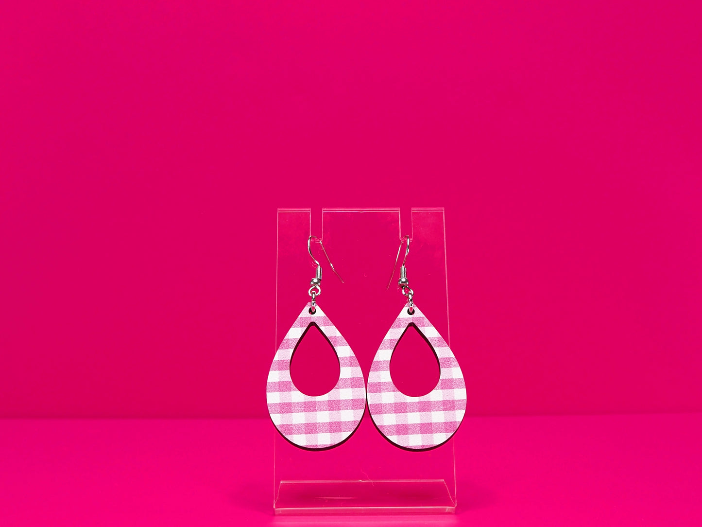Light punk gingham tear drop earrings on a clear display against a hot pink background.