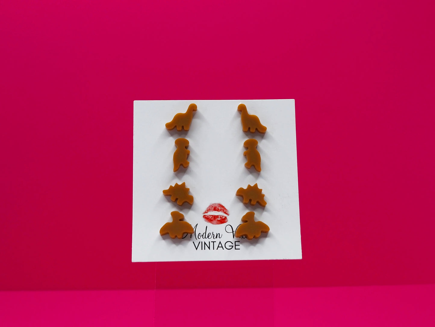 Set of 4 dinosaur earrings on a card with 'Modern Vintage' branding against a pink background.