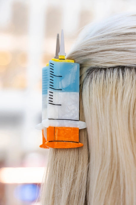 Syringe hair claw in blonde hair against a light background
