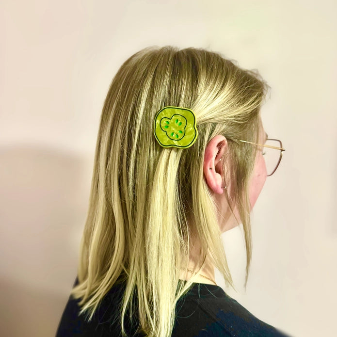Blonde model with pickle clip in their hair against a light background.