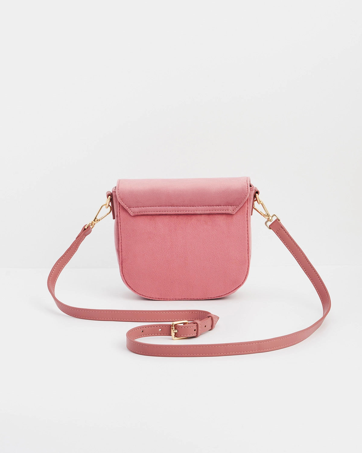 Back of pink saddle bag with pink purse strap against a white background.