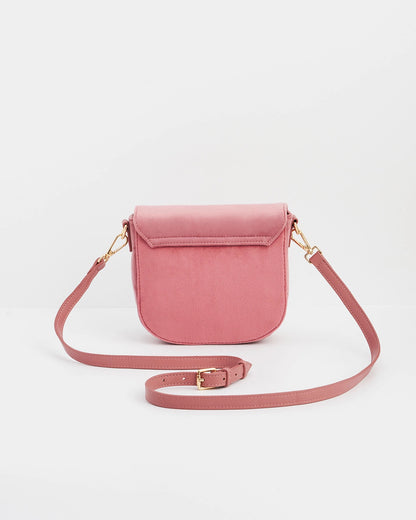 Back of pink saddle bag with pink purse strap against a white background.