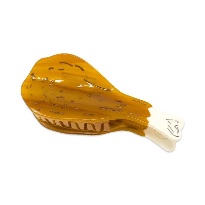 Drumstick hair claw at an angle showing teeth of hair claw against a white background.