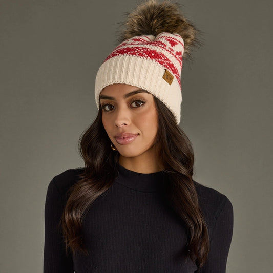 Woman wearing a patterned knit beanie with a pom-pom on a gray background.