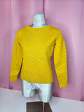 Sweater on mannequin at an angle against a pink background 