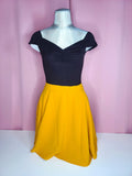 Top on mannequin with a skirt against a pink background 