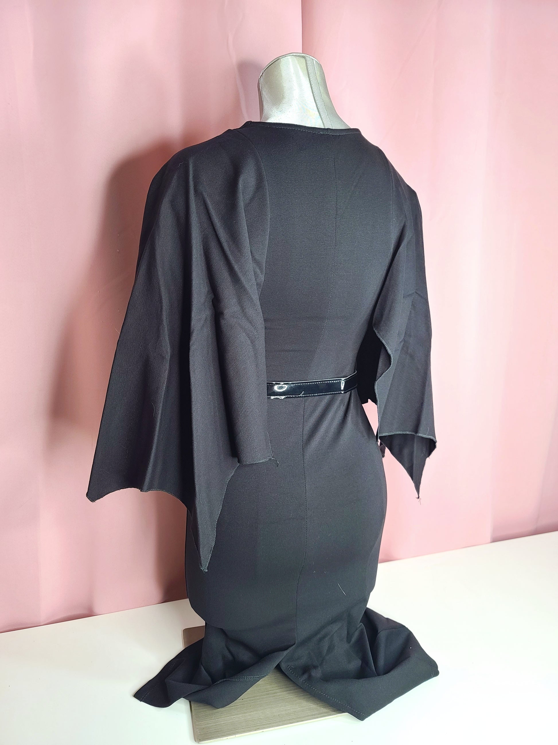 Back of dress at an angle on a mannequin against a pink background 