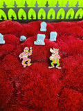 Both pins against a red faux graveyard