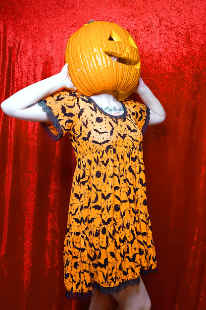 Model wearing a jack o lantern head showcasing dress against a red background