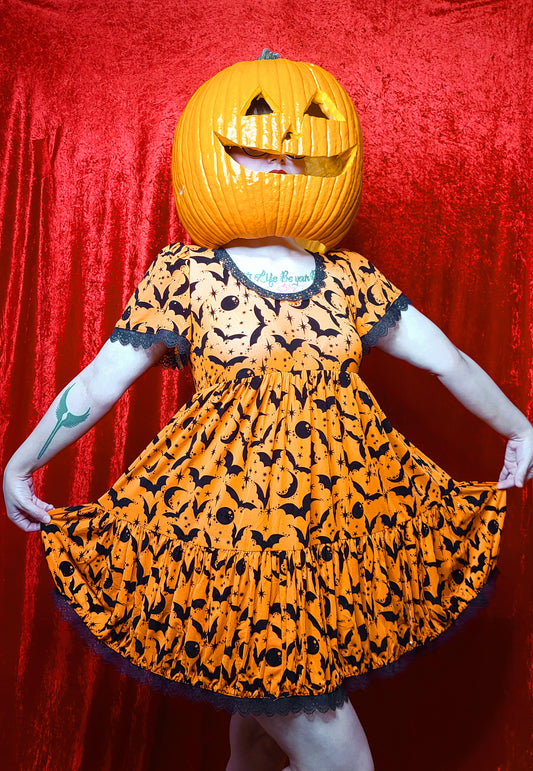 Model wearing a jack o lantern head showcasing dress against a red background