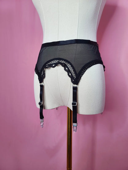 Close up of garter on a white mannequin against a pink background 