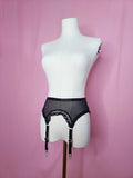 Garter on a white mannequin against a pink background