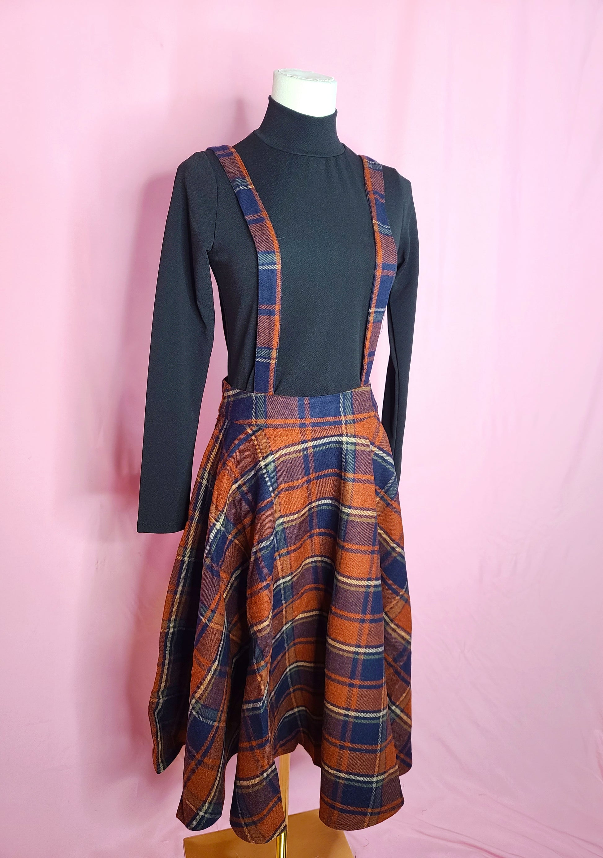 Skirt shown with black mock neck top against a pink background