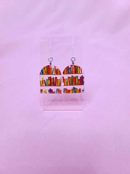 Earrings on a clear earring display against a bright pink background