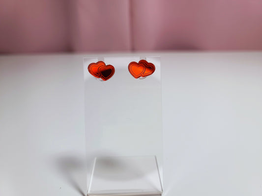 Earrings on a clear earring display against a pink and white background