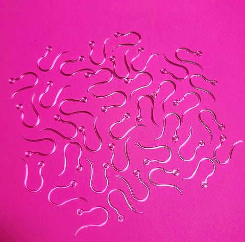 A group of plastic earrings hooks against a dark pink background