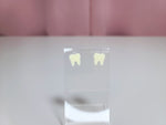 Earrings on a clear display against a pink and white background