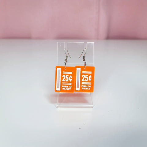Earrings on a clear display against a white and pink background