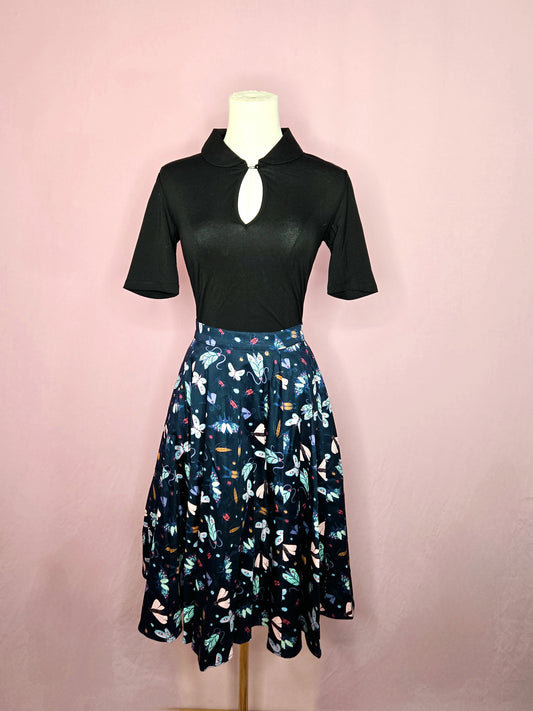 Skirt paired with the Keynote Blouse in Black on a white mannequin against a pink background