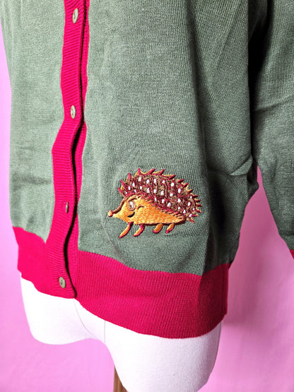 Close up of the hedgehog along the bottom of the cardigan against a pink background