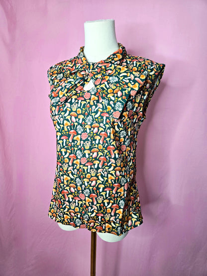 Front of the blouse at a slight angle on a white mannequin against a pink background