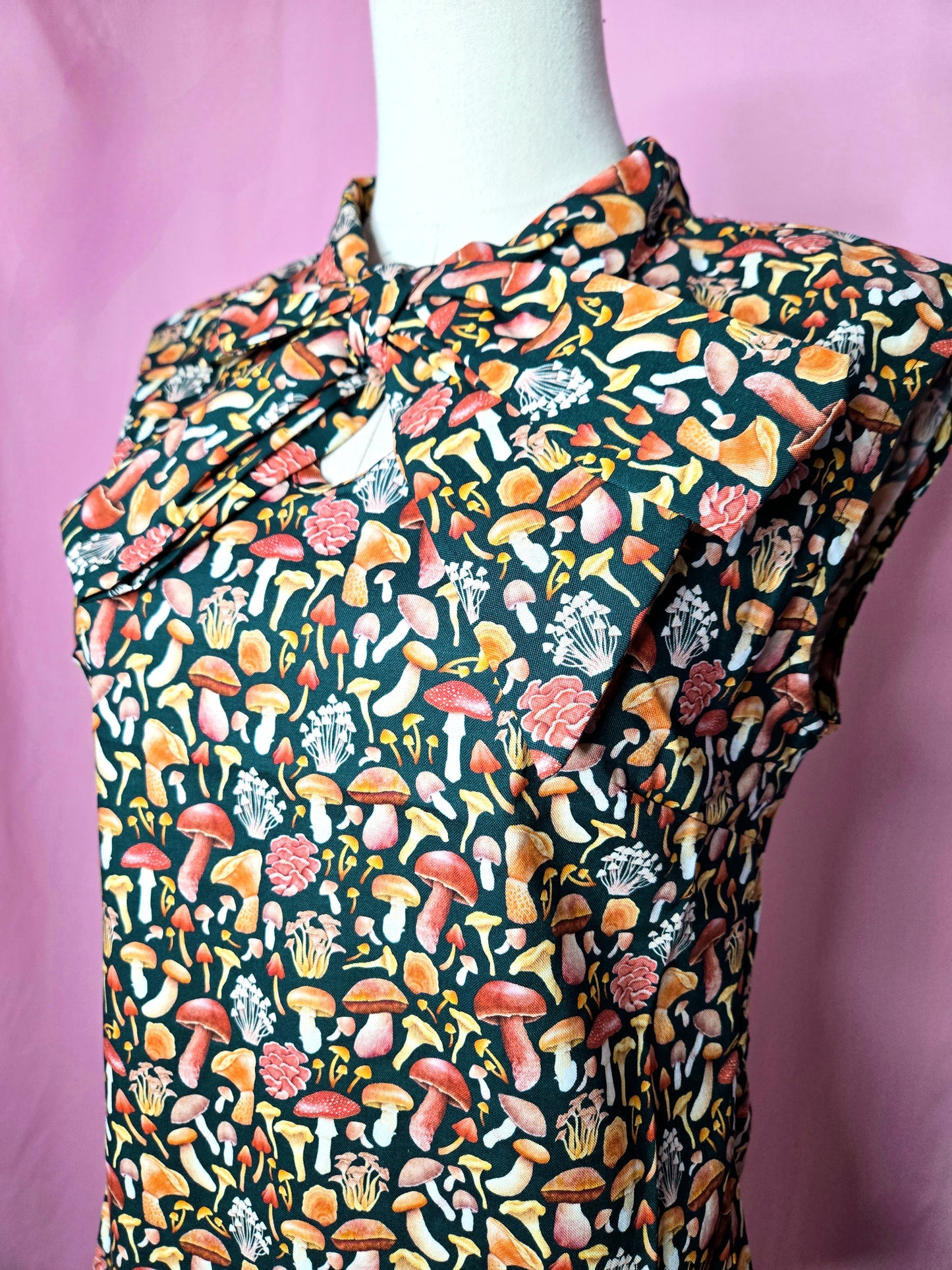 Close up of the blouse to show the mushroom print. Blouse is on a white mannequin against a pink background