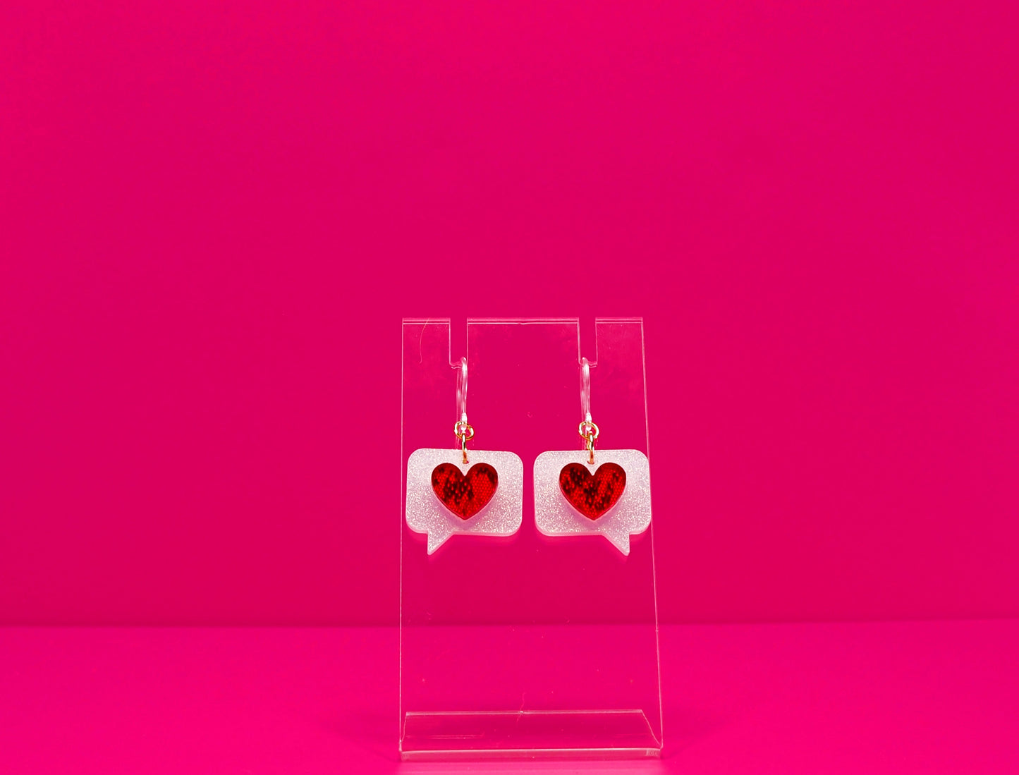 Red hearts on white text bubble earrings on a clear display against a pink background. Shown with plastic hook option.