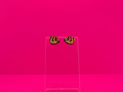 Pair of brown wood sloth earrings on a clear display against a hot pink background.