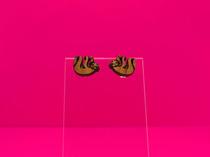 Pair of brown wood sloths on a clear display against a hot pink background.