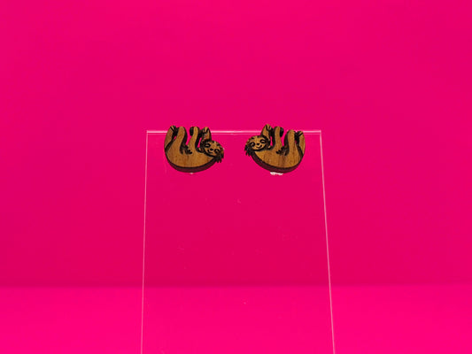 Pair of brown wood sloths on a clear display against a hot pink background.