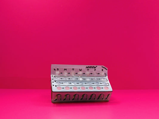 Birth control hair claw against a pink background.