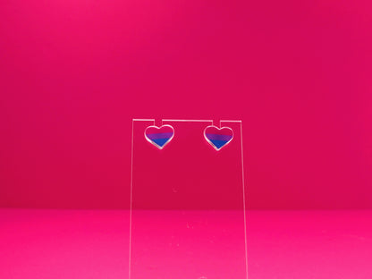 Bisexual pride heart earrings on a clear display against a pink background.