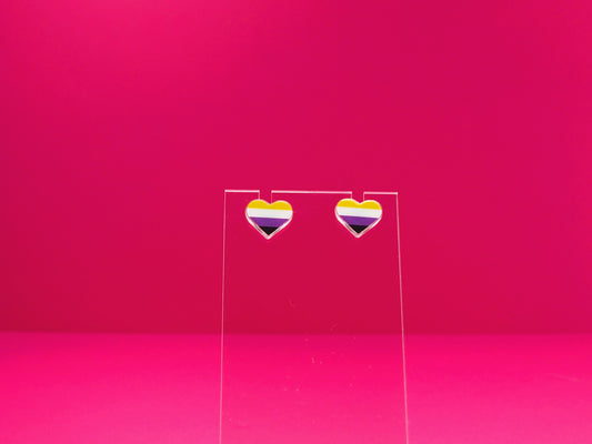 Non-binary pride heart earrings on a clear display against a pink background.