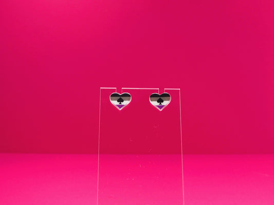 Ace pride heart earrings on a clear display against a pink background.