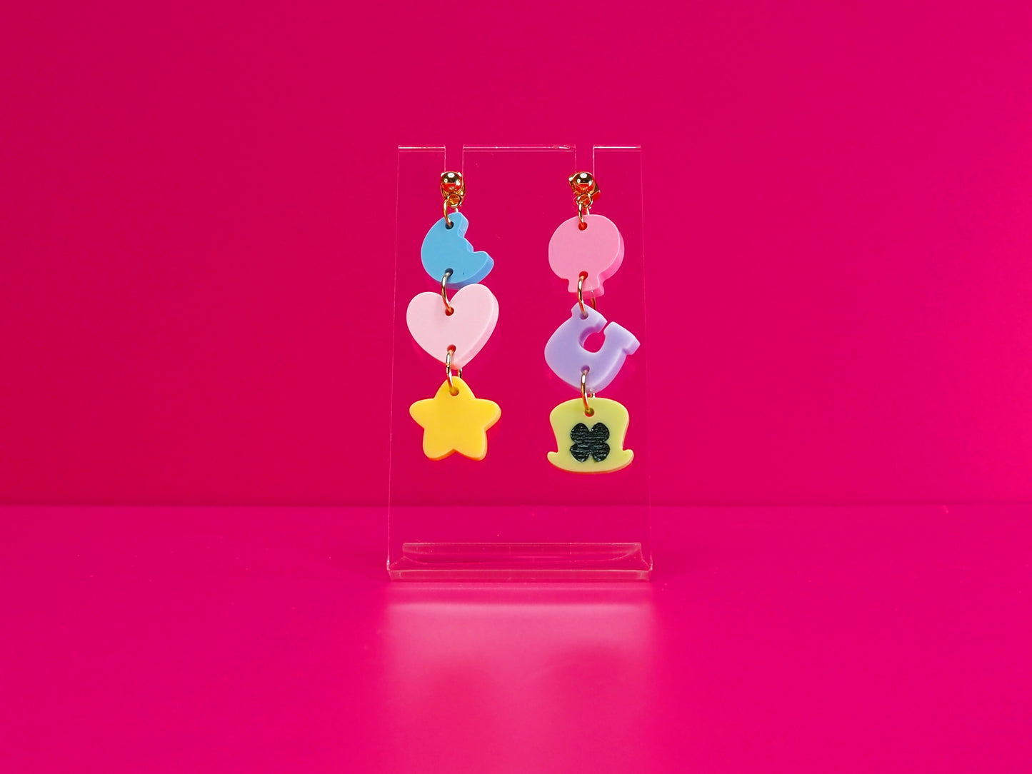 Cereal earrings on a clear stand against a pink background.