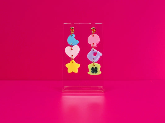 Cereal earrings on a clear stand against a pink background.