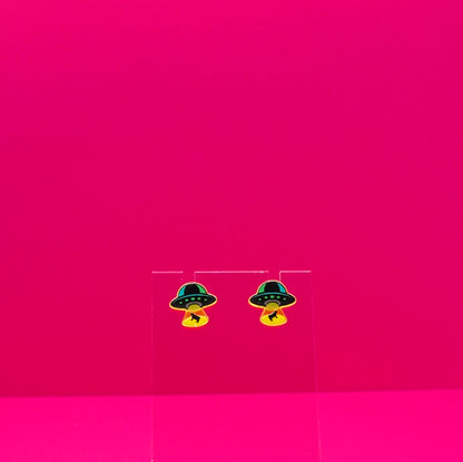 UFO abducting cows on a clear stand against a pink background.