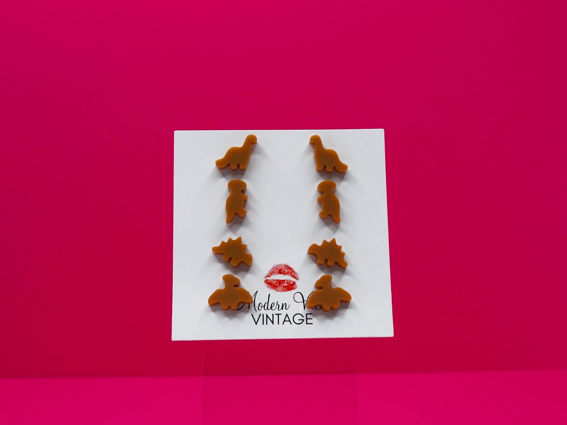 Set of 4 dinosaur earrings on a card with 'Modern Vintage' branding against a pink background.