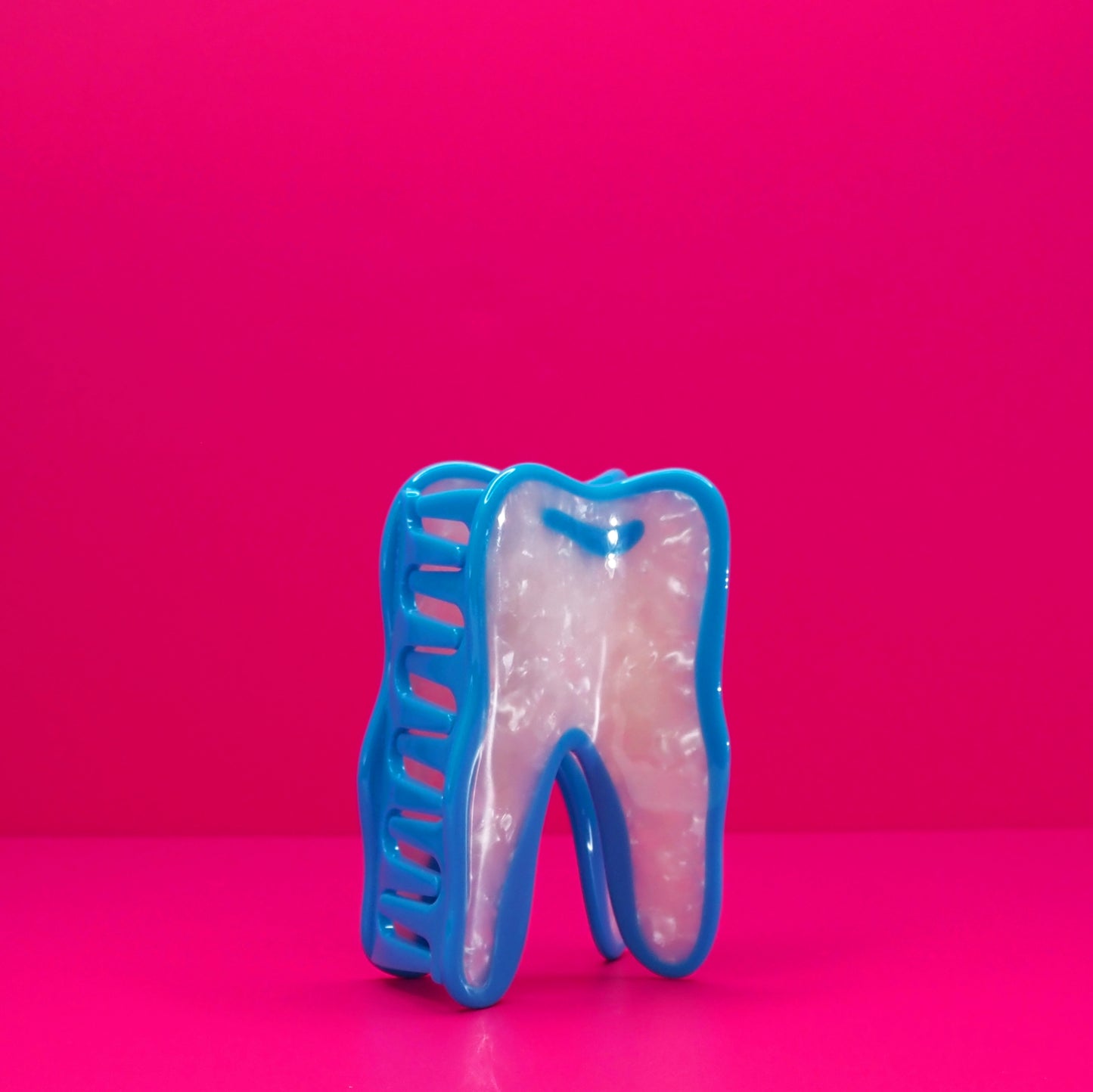 Wisdom tooh hair claw at an angle against a pink background.