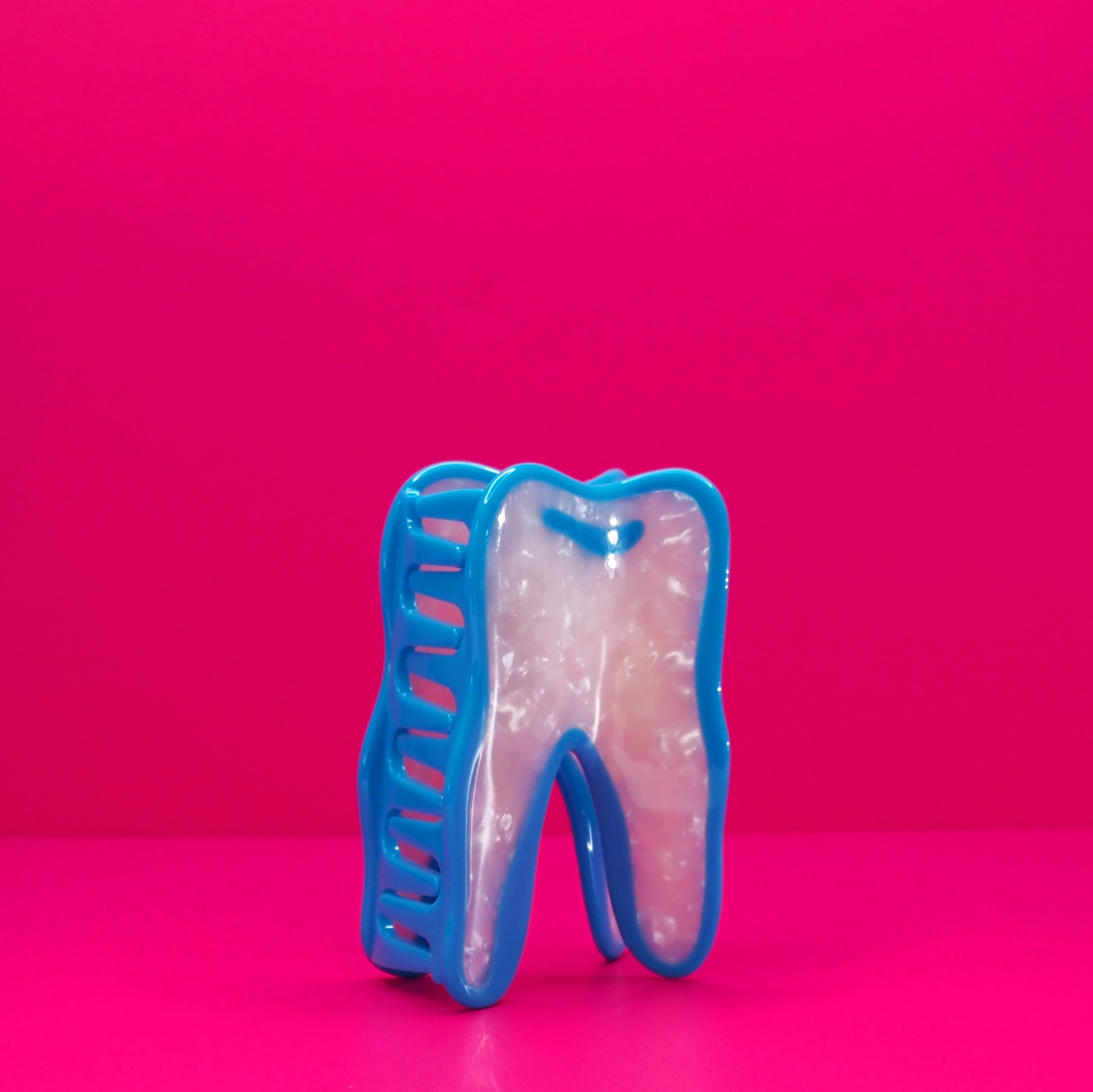 Wisdom tooh hair claw at an angle against a pink background.