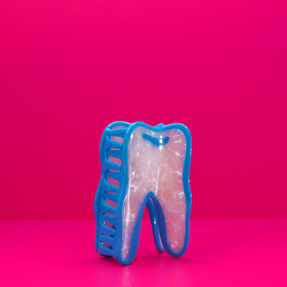 Wisdom tooh hair claw at an angle against a pink background.
