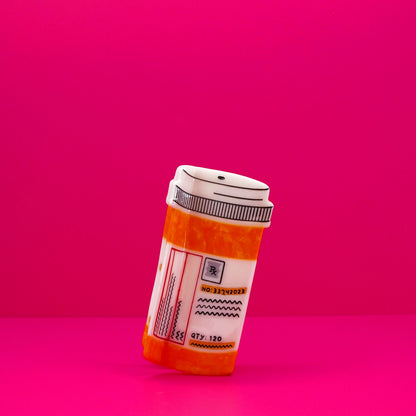 Orange and white prescription bottle hair claw against a pink background.