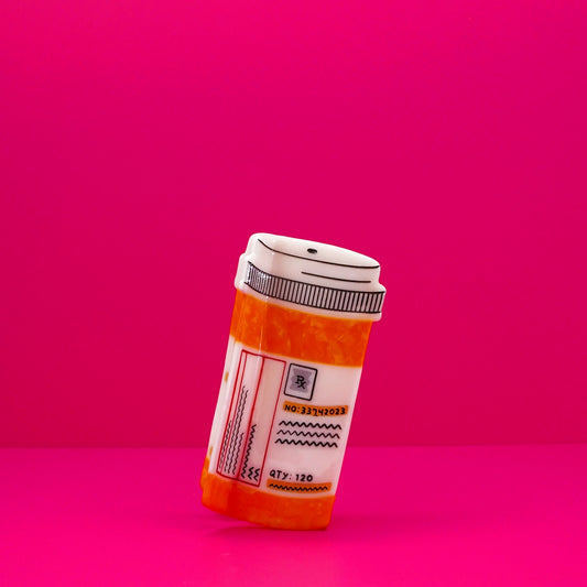 Orange and white prescription bottle hair claw against a pink background.