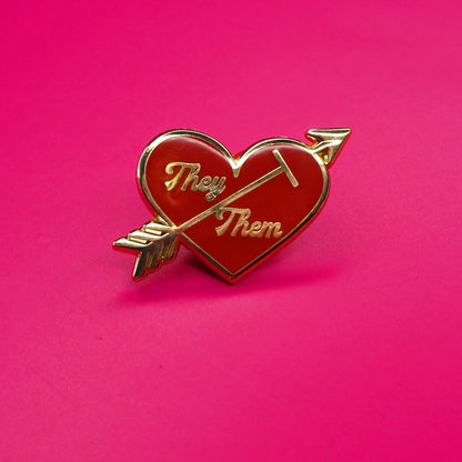 Heart-shaped pin with 'They' and 'Them' text on a pink background.