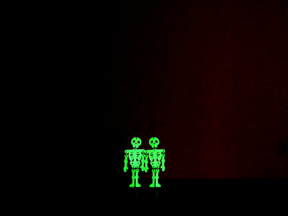 Skeleton earrings in the dark to show their green glow against a dark background.