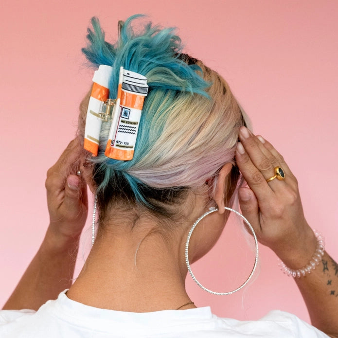 Hair claw worn in blue and blonde hair against a pink background.