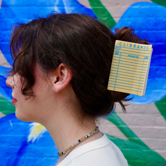 Brunette hair model wearing the library card hair claw against a colorful background.