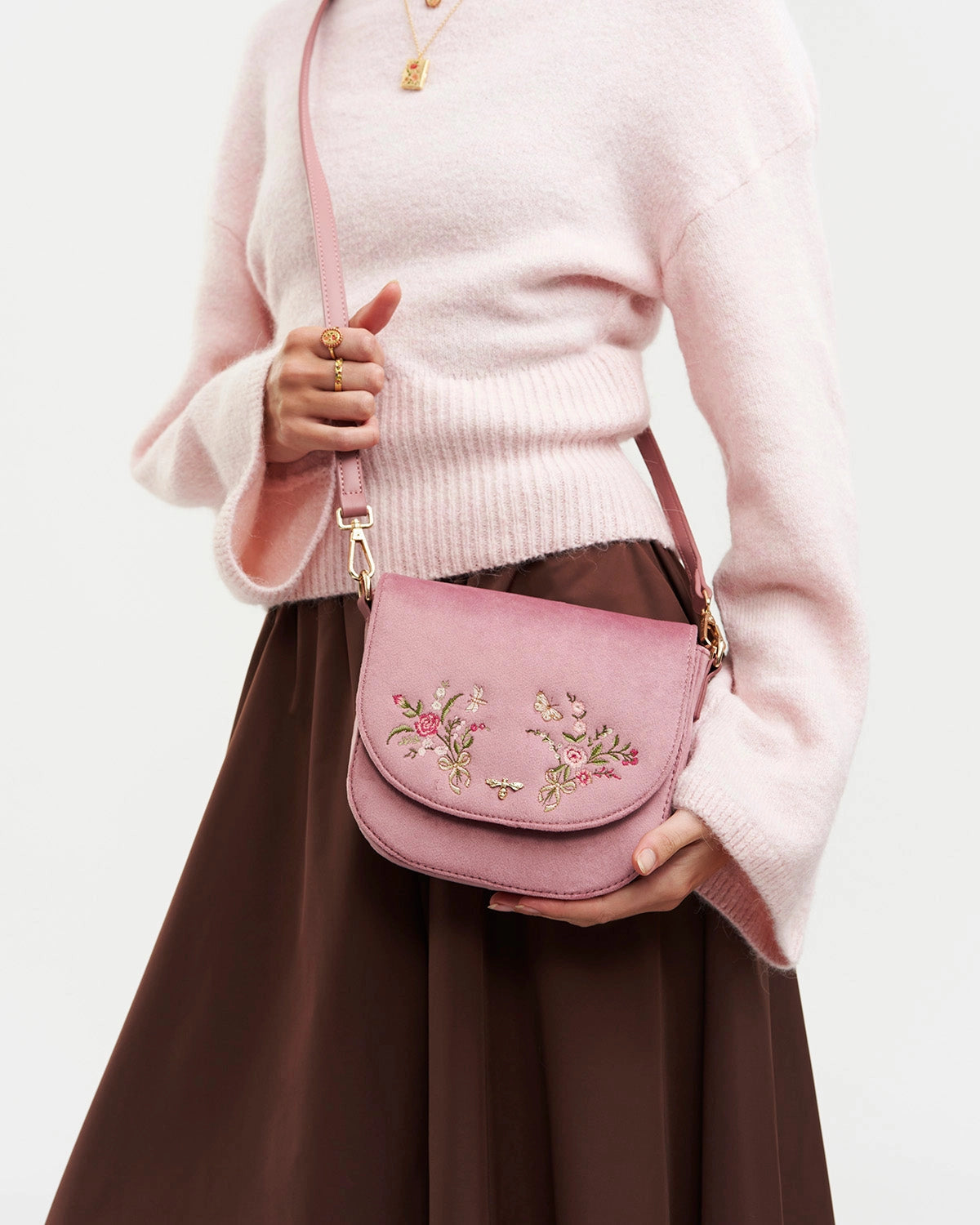 Model wearing purse at side against a white background.