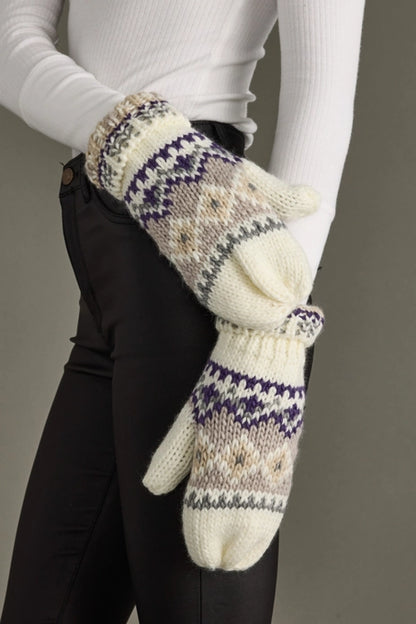 Pair of knitted mittens with a pattern worn by a person against a neutral background.