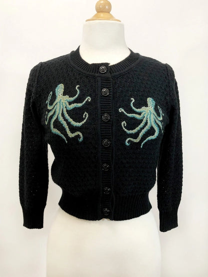 Black cardigan with a green octopus on both sides of the front near the top of the cardigan. Cardigan is on a light colored mannequin against a white backgorund